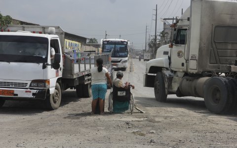 Dos personas piden caridad en la intersección de las avenidas Juan Bosco y la 25 de Julio, en medio de vehículos pesados y el polvo.