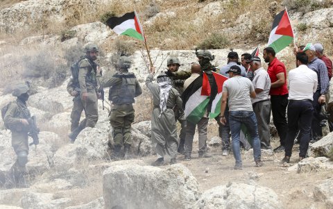 Manifestantes palestinos, algunos con banderas palestinas, discuten con soldados israelíes durante enfrentamientos en la zona de la aldea de Beit Dajan.