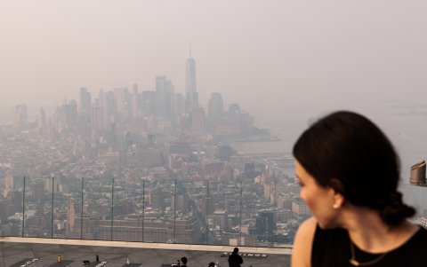 Una mujer mira el horizonte de Manhattan envuelto en neblina causada por el humo de los incendios forestales en Canadá, en Nueva York, EE. UU., 07 de junio de 2023