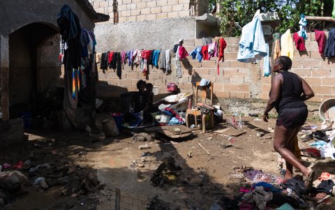 Una mujer camina entre ropa y enseres dañados por el lodo producto de las intensas lluvias en Haití.