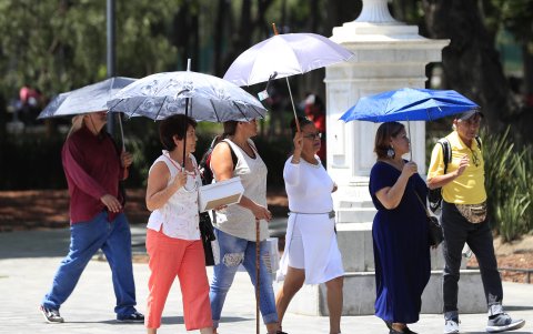Personas se protegen del sol con sombrillas, el 14 de junio de 2023, en la Alameda Central la Ciudad de México (México).