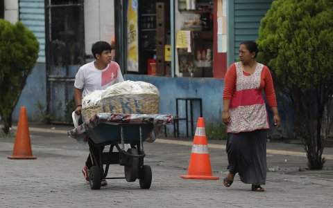San Salvador. Un menor traslada mercadería entre los vehículos estacionados en una esquina de esta capital centroamericana.