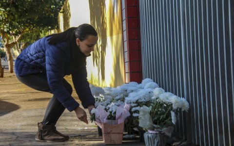 Personas ponen flores en la entrada de la escuela Profesora Helena Kolody, donde dos jóvenes fueron asesinados el 19 de junio de  2023  por un exalumno del centro educativo, en Cambé (Brasil)