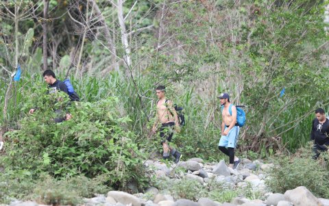 Un grupo de migrantes avanza en medio de piedras, maleza y la humedad de la selva.