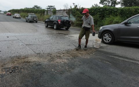 Julio Macías, un obrero que rellena con tierra los enormes baches de la Teodoro Alvarado Oleas.