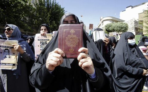 Mujeres iraníes sostienen ejemplares del libro sagrado del Corán y carteles mientras se manifiestan frente a la embajada de Suecia en Teherán