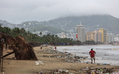 Personas caminan por una playa llena de basura debido a las fuertes lluvias  del viernes 30 de junio de 2023 , en el balneario de Acapulco, estado de Guerrero (México).