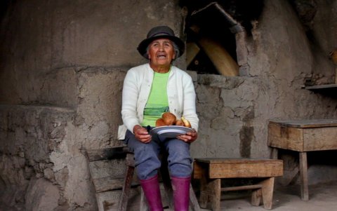 Una mujer indígena descansa al pie de uno de los hornos de leña que conforman la ruta del trigo.