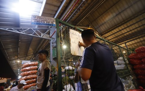 Comercio. Una persona borra a lo apurado el precio de la cebolla, por la presencia de la autoridad en el mercado.