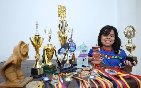 El niño muestra con orgullo las medallas y trofeos que ha ganado en las diferentes competencias.