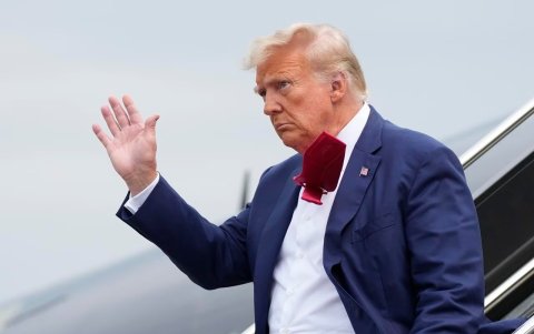 Donald Trump saluda a los presentes mientras se baja de su avión, en su camino a enfrentar un juez por acusaciones federales de conspirar para revertir las elecciones 2020.