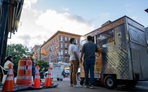 Dos personas compran comida en un puesto móvil llamado 'Antojitos Dominicanos' en un sector conocido como la Pequeña Dominicana, el 8 de agosto de 2023, en Nueva York (EE.UU.).
