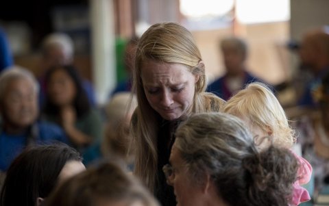 Una habitante desplazada de Lahaina reacciona mientras saluda a otros feligreses cuando llegan para un servicio conmemorativo en el Maui Coffee Attic que alberga el servicio dominical.