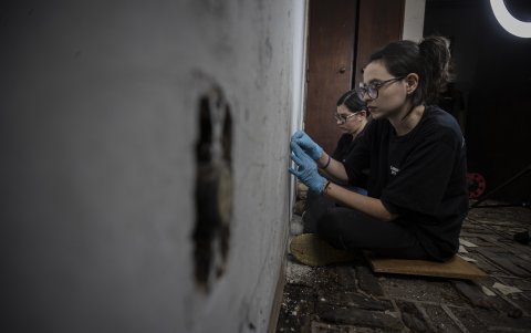 Arqueólogas. Raspan con bisturí capas de pintura de una de las antiguas celdas buscando inscripciones.