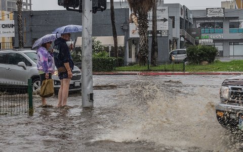 Una pareja sale de compras por una calle inundada tras el paso de la tormenta Hilary en la ciudad de Tijuana (México).