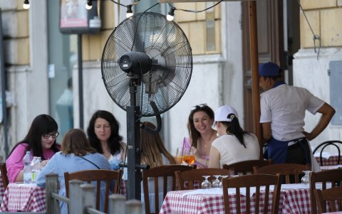 Turistas en un restaurante se refrescan con un ventilador, este viernes en Roma.
