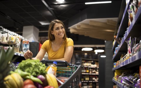 Woman with shopping cart buying food at supermarket.