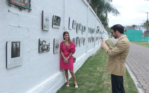 Carlos Ortega Santos le toma fotos a su cuñada Claudia Garzozi, quien posa junto a una foto en la que aparece el local  Jaime Puig Verdaguer & Cía., propiedad de su tatarabuelo.