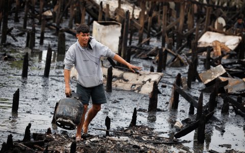 Un chico  observa los escombros  y busca objetos tras un incendio de grandes proporciones que destruyó más de 100 viviendas de madera  en Santo (Brasil).