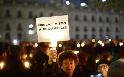 Una mujer levanta un cartel en rechazo a la dictadura de Augusto Pinochet.