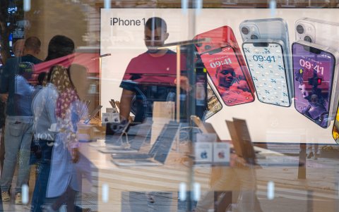 Varios compradores aparecen en una tienda de la tecnológica estadounidense Apple, con publicidad de sus iPhones en el fondo.