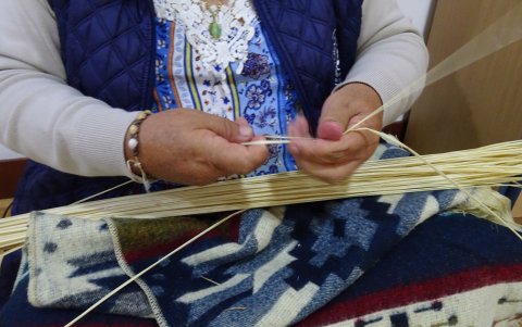 Primer plano. Las manos hábiles de Blanca Guambaña trenzan las hebras de la paja para iniciar con el tejido de los sombreros de toquilla.