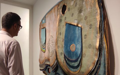 Un visitante observa la obra textil de la artista brasileña Leda Catunda, una delicada pieza textil hecha a capas.