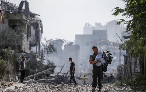 Palestinos caminan entre ruinas en el barrio de Al Ramal de Gaza tras un bombardeo israelí.
