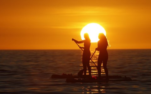 Dos adolescentes practican el paddel surf en la ría de Muros y Noia, en Portosín.