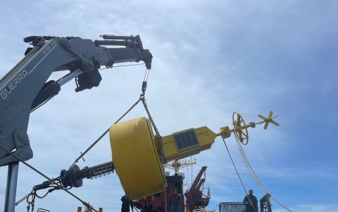 Una grúa traslada la boya del barco al agua.