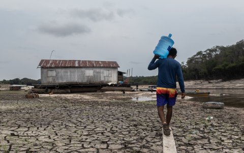 Un hombre llevando agua a una casa flotante varada en una zona conocida como Marina do Davi, hoy en Manaos, Amazonas, Brasil.