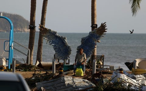 Una persona permanece sentada junto a los escombros causados por el huracán Otis en Guerrero (México)