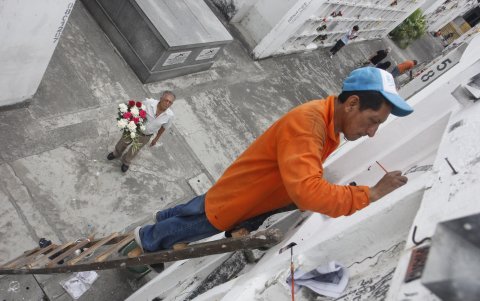 Pintar. Milton Tinoco contrató un pintor para que retoque las letras de la lápida de la tumba su abuela y le llevó flores.