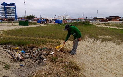 Un servidor turistico recoge la basura acumulada en la playa.