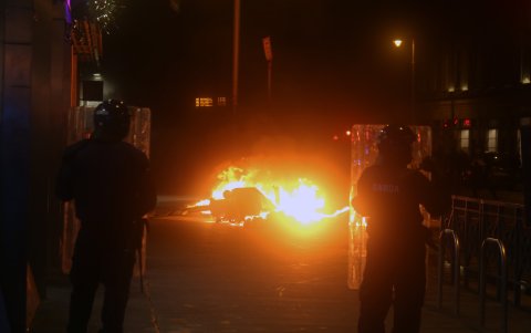 Dublín. Elementos policiales observan desde lejos cómo arde el fuego en un área urbana de esta capital europea.