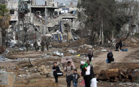 Palestinos caminan después de cruzar desde el norte de la Franja de Gaza al sur de la Franja de Gaza mientras los soldados israelíes avanzan por la carretera Salah Al Din.