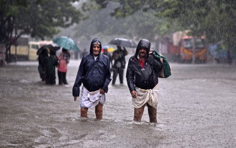 Una par de personas camina por una calle inundada a causa del ciclón Michaug Chennai (India).