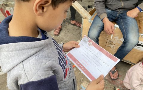 Uno de los hijos de Ayad, con una papeleta lanzada por la aviación israelí, pidiendo evacuar a Rafah, este miércoles, 6 de diciembre de 2023.