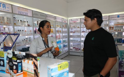 -Farmacia. María Fernanda Coronel, experta en cuidado de la piel, de Fybeca explica a un cliente el tipo de protector solar que debe usar.