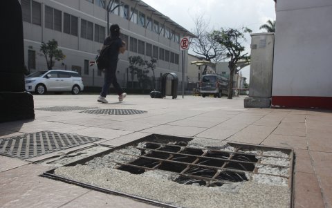 Aceras. Alcantarillas con huecos y baldosas rotas se observan en la vía.