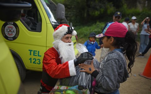 Niños y niñas de escasos recursos del asentamiento Jesús de la Esperanza reciben hoy regalos de parte de Héctor Chacón, mayor de los Bomberos Municipales, en Ciudad de Guatemala (Guatemala).