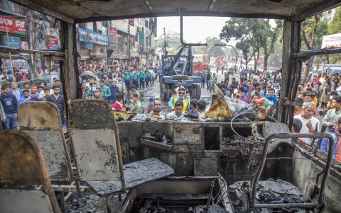Decenas de personas se amontonan alrededor del autobús incendiado este 19 de diciembre de 2023 en la ciudad de Dacca.