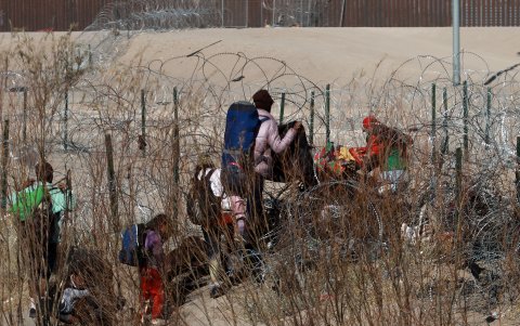 Migrantes intentan cruzar la cerca de alambres en la frontera que divide a México de los Estados Unidos, el 17 de enero de 2024, en Ciudad Juárez (México).
