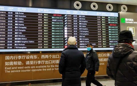 La gente mira la pantalla de llegadas nacionales en el Aeropuerto Internacional Daxing de Beijing, China, 26 de enero de 2024.