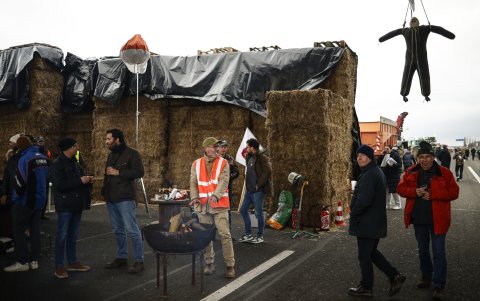 Los agricultores franceses se reúnen cerca de un fuego ardiente y un fardo de paja en el punto de bloqueo de la autopista A4 en Jossigny, al este de París, Francia, el 30 de enero de 2024.