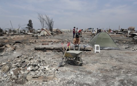 Personas del campamento irregular “Pompeya” recogen escombros, tras los incendios del día viernes 2 de febrero, en la zona de Viña del Mar.