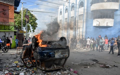 Policías vigilan a manifestantes que participan de una gran protesta antigubernamental hoy, en Puerto Príncipe (Haití).