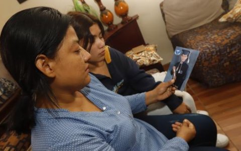 La madre de Carlos sostiene una foto de su hijo, recordándolo durante su época colegial.