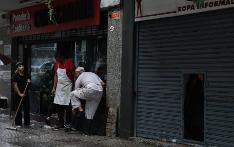 Personas sacan el agua de sus locales por las fuertes lluvias, en Buenos Aires