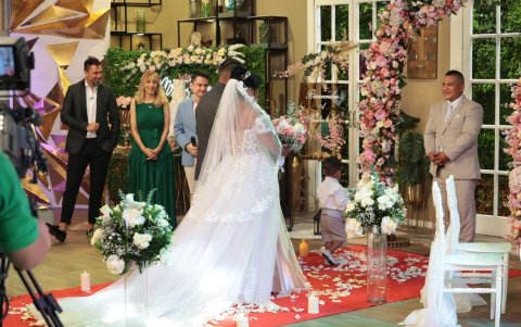 La novia camina por la alfombra roja llena de flores.